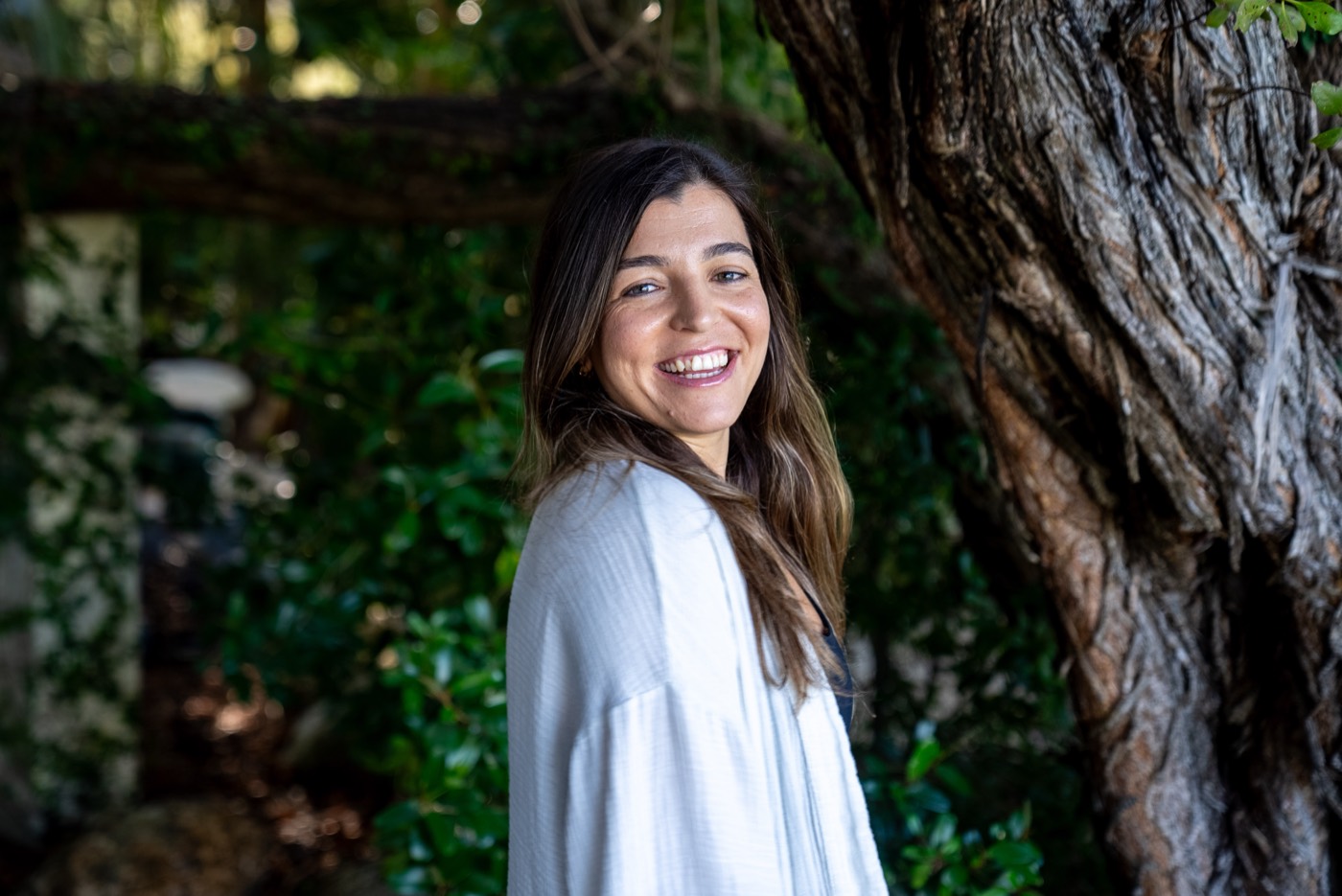 Kensey, founder of AERA, smiling outdoors among trees